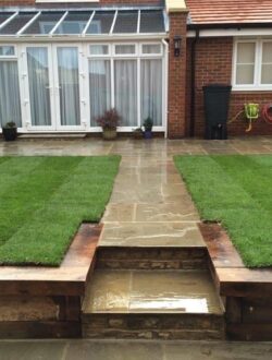 Raj Green Sandstone patio with raised sleeper edge in Abbots Langley garden