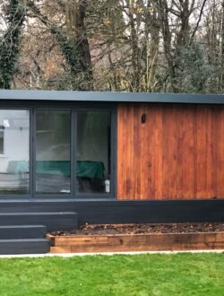 Contemporary cedar-clad garden room with composite steps and lawn