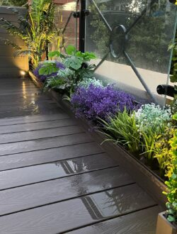 Close-up of composite deck boards and raised planter with artificial flowers