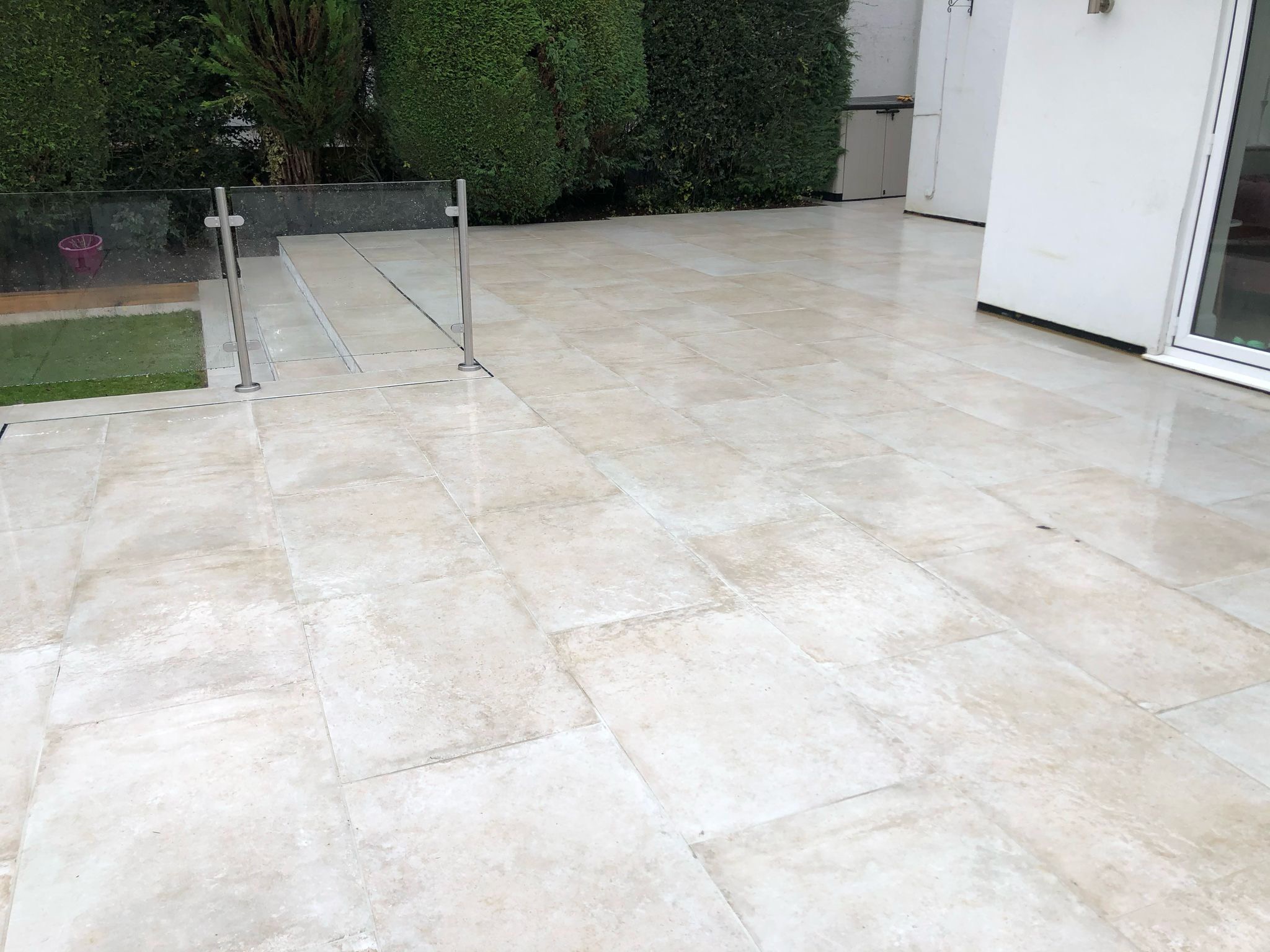 Modern garden design with porcelain patio, artificial lawn, glass balustrade and bespoke garden room